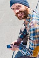 Urban lifestyle. Top view of handsome young man sitting and writing a message photo