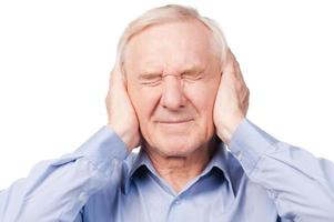 This is too loud Frustrated senior man in shirt holding head in hands and keeping eyes closed while standing against white background photo