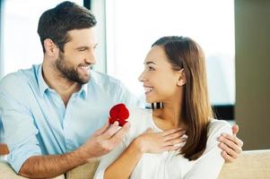 Please say yes Handsome young man making a proposal while giving an engagement ring to his girlfriend photo