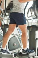 Exercising on step machine. Cropped image of man doing cardio exercise on step machine photo