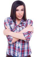 Feeling freezy. Beautiful young woman freezing while keeping arms crossed and standing isolated on white photo