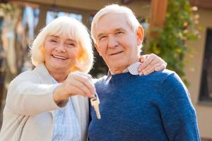 Happy seniors. Happy senior couple bonding to each other and smiling while woman holding keys in her hand photo