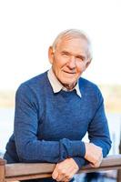 Confident senior man. Confident senior man looking at camera and smiling while standing outdoors photo