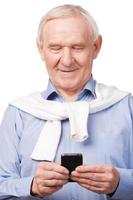 Modern senior man . Happy senior man holding mobile phone while standing against white photo