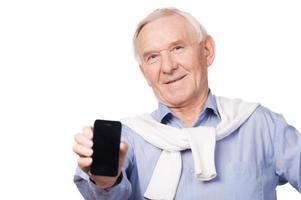 Copy space on my telephone. Portrait of happy senior man showing his mobile phone while standing against white background photo