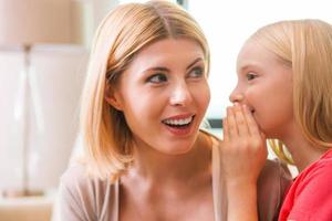 Sharing secrets with mom. Happy mother and daughter sharing secrets while sitting at home together photo