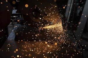 Sparks from grinder. Metal cutting. Bright lights in dark. Industrial background. photo