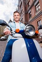 la libertad está en mis venas vista en ángulo bajo de un joven apuesto montando scooter por la calle y sonriendo foto