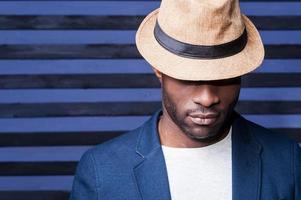 Man in style. Handsome young African man in hat standing against striped background photo