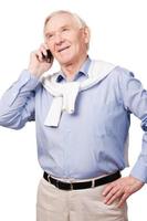 Senior man on the phone. Portrait of happy senior man smiling at camera while standing against white background photo