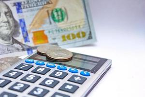 Calculator and dollar bills are placed on a white table. photo