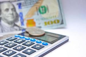 Calculator and dollar bills are placed on a white table. photo