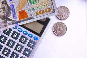 Calculator and dollar bills are placed on a white table. photo