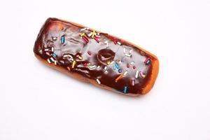 barra de donut de chocolate cubierta con copos de azúcar multicolores. colocado sobre un fondo blanco foto
