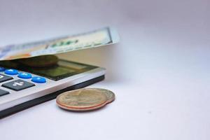 Calculator and dollar bills are placed on a white table. photo