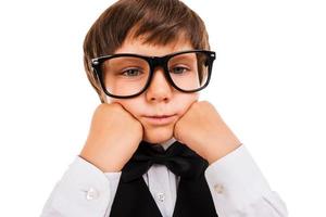 Tired schoolboy. Bored little boy leaning his face on hands and looking at camera while isolated on white photo