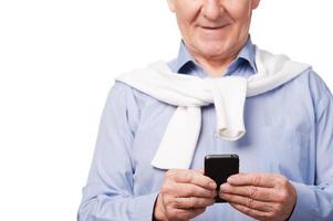 Modern grandfather. Happy senior man holding mobile phone while standing against white background photo