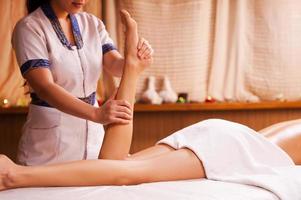eliminando el estrés. vista superior del terapeuta de masaje masajeando hermosa pierna femenina foto