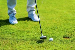 casi adentro. primer plano del hombre jugando al golf mientras está parado en green y cerca del hoyo foto