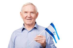 hombre mayor con bandera israelí. un anciano alegre que sostiene la bandera de Israel y sonríe a la cámara mientras se enfrenta a un fondo blanco foto