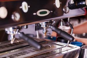 Coffee maker. Close-up image of metal espresso machine with someone working in the background photo