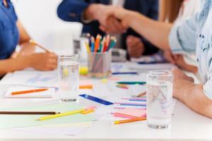 Working moments. Close-up of business people in smart casual wear shaking hands while sitting at the table together photo