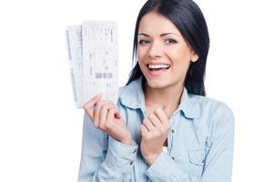 Going on vacations. Beautiful young woman holding tickets and smiling while standing against white background photo