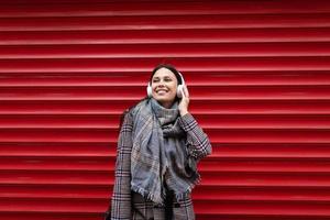 retrato de una joven alegre con auriculares en el fondo de una pared roja en relieve foto