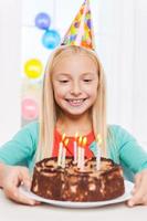 feliz cumpleaños para mí niña feliz mirando el pastel de cumpleaños y sonriendo foto