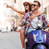 Just look at that Beautiful young couple riding scooter together while happy woman pointing away and smiling photo
