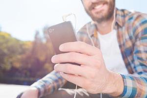 Enjoying the rhythm of his life. Close-up of handsome young bearded man smiling while listening to music photo