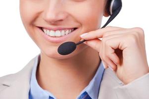 How may I help you Close-up of young customer service representative adjusting her headset and smiling while standing against white background photo