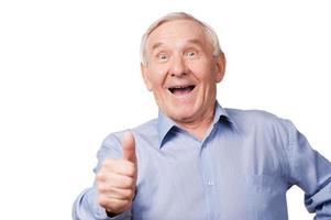 It is cool Excited senior man stretching out his hand with thumb up while standing against white background photo
