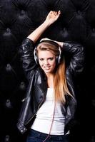 Music lover. Beautiful young woman with make up and in headphones posing against black background photo