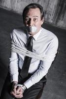 Feeling shocked and hopeless. Top view of tied up businessman with adhesive tape on his mouth looking up with shock photo