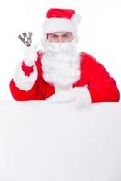 Merry Christmas Traditional Santa Claus ringing a bell while leaning at the copy space and being isolated on white photo