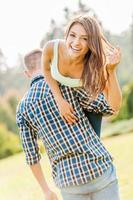 Happy loving couple. Young man holding beautiful cheerful girl on his shoulder photo