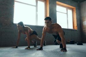 Young fit couple looking concentrated while exercising in gym together photo