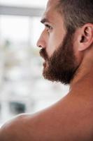 Manly and confident. Rear view of thoughtful young bearded and shirtless man looking away photo