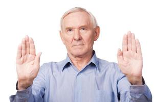 Stop it Serious senior man in shirt showing his palms and looking at camera while standing against white background photo