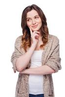 Lost in thoughts. Beautiful young woman holding hand on chin and looking away while standing isolated on white photo