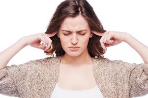 Too loud sound. Frustrated young woman covering ears with hands and keeping eyes closed while standing isolated on white photo