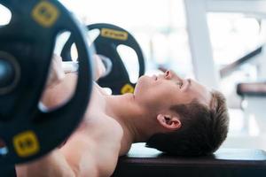 Bench press. Confident young muscular man working out on bench press photo