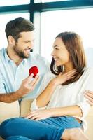 Will you marry me Handsome young man making a proposal while giving an engagement ring to his girlfriend photo