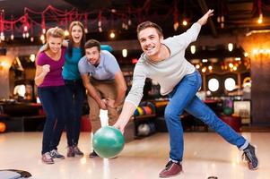 el es un ganador jóvenes guapos lanzando una bola de bolos mientras tres personas animan foto