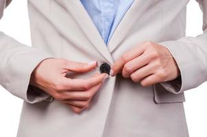 Making business look great. Close-up of young businesswoman buttoning her jacket while standing against white background photo