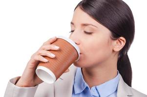 descanso. joven empresaria segura de sí misma bebiendo café mientras se enfrenta a fondo blanco foto