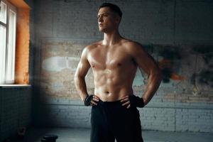 Handsome muscular man holding hands on hip while standing in gym photo