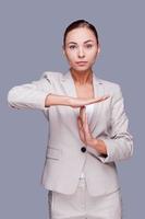 Time out Confident young businesswoman gesturing time out  sign while standing against grey background photo