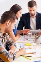 Concentrated on work. Three confident business people in smart casual wear working together while sitting at the table photo